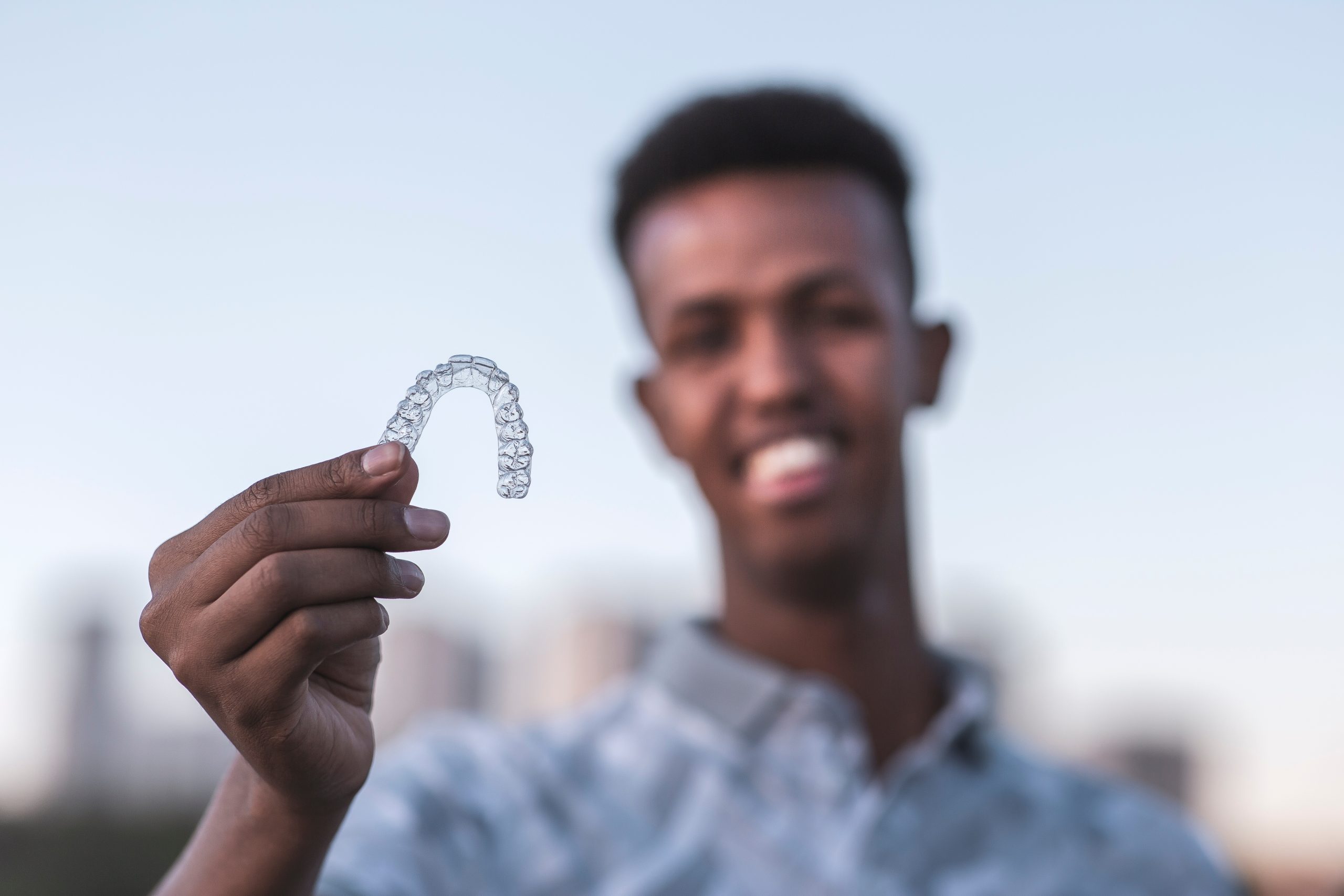 Young black man is holding an invisalign brace and he has confident smiling